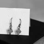 black and white photo of earrings on white card.